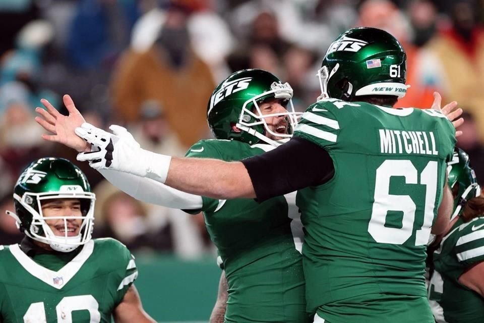 Aaron Rodgers (al centro), de los New York Jets, celebra después de lanzar su pase de touchdown número 500 de su carrera contra los Miami Dolphins.