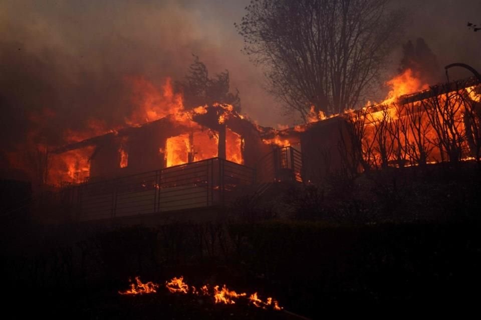 Llamas de un incendio forestal consumen una casa en el vecindario Pacific Palisades, en Los Ángeles.