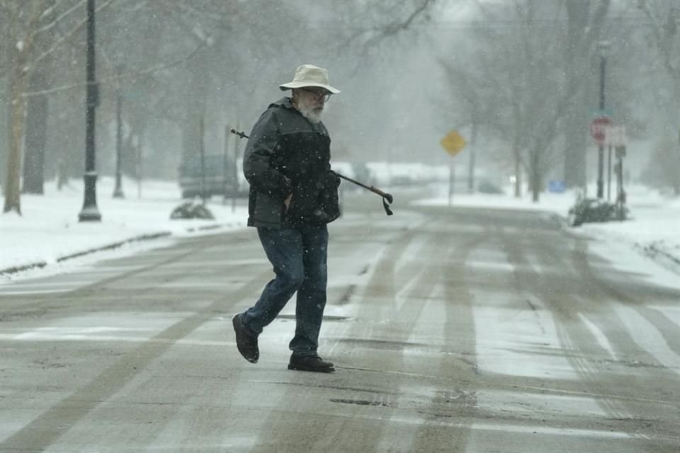 Seorang pria menyeberang jalan saat hujan salju di Illinois pada 12 Januari 2025.