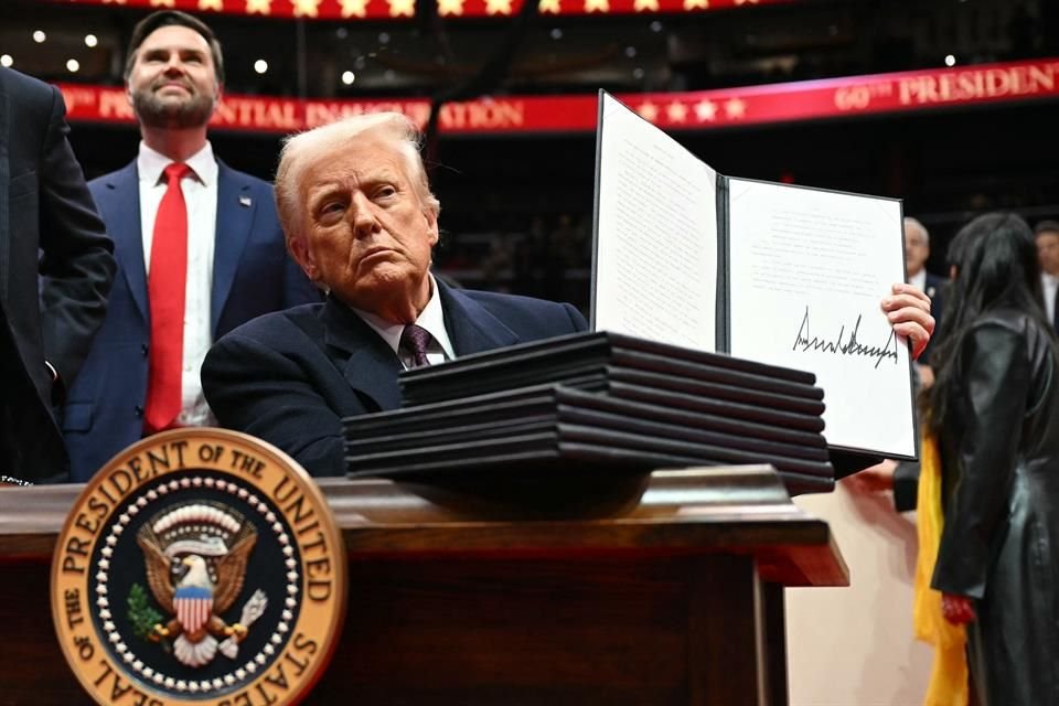 El Presidente Donald Trump sostiene una orden ejecutiva durante un evento en la Capital One Arena.