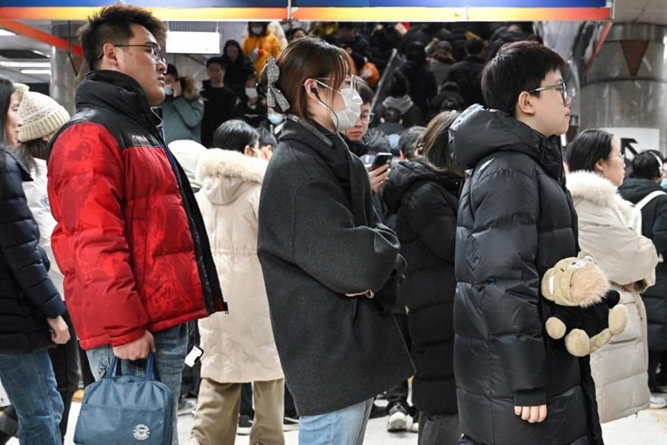 Zhang Yachun (dcha.) con su robot dotado de Inteligencia Artificial llamado Aluo mientras hace cola para entrar al metro, en Pekín, China.