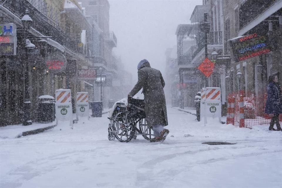 Un hombre empuja una silla de ruedas durante una nevada en Bourbon Street, en Nueva Orleans, el 21 de enero del 2025.