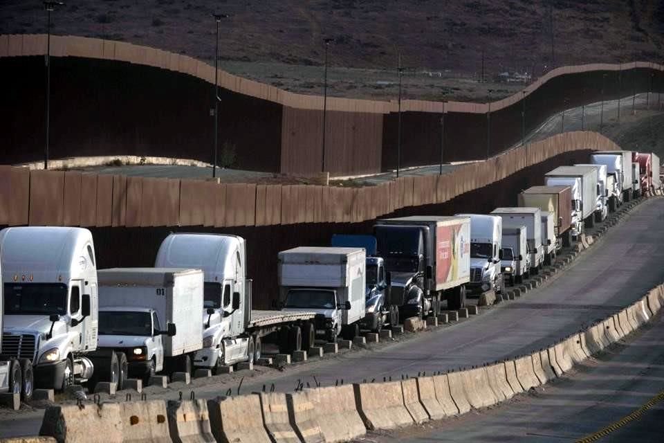 Camiones hacen fila junto al muro fronterizo antes de cruzar a Estados Unidos en el puerto comercial de Otay en Tijuana.