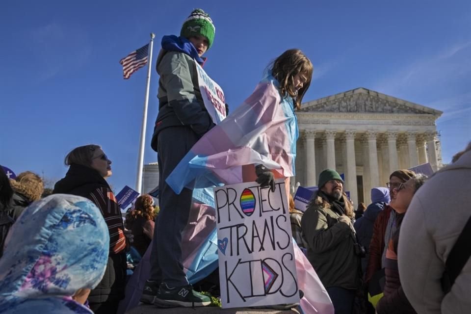 Dos niños sostienen pancartas y una bandera trans durante una protesta afuera de la Suprema Corte, el 4 de diciembre del 2024.