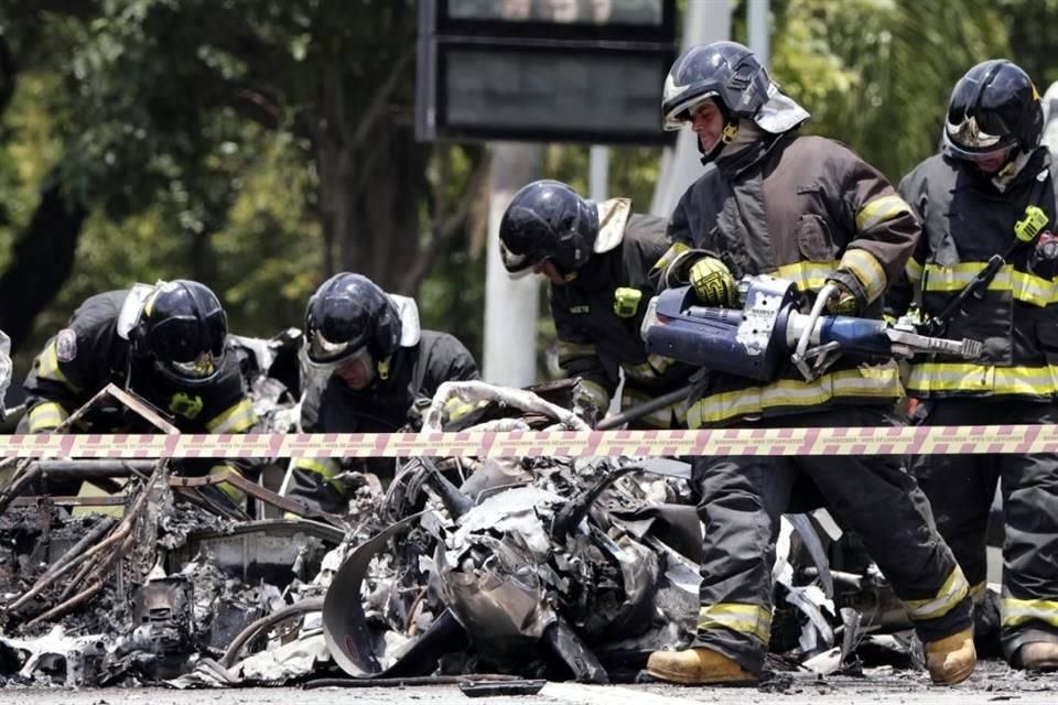 Los bomberos inspeccionan una avioneta que se estrelló en una avenida de Sao Paulo.