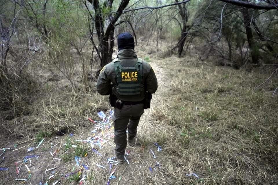 Un agente de la patrulla fronteriza camina por un sendero lleno de brazaletes utilizados por grupos de tráfico de personas.