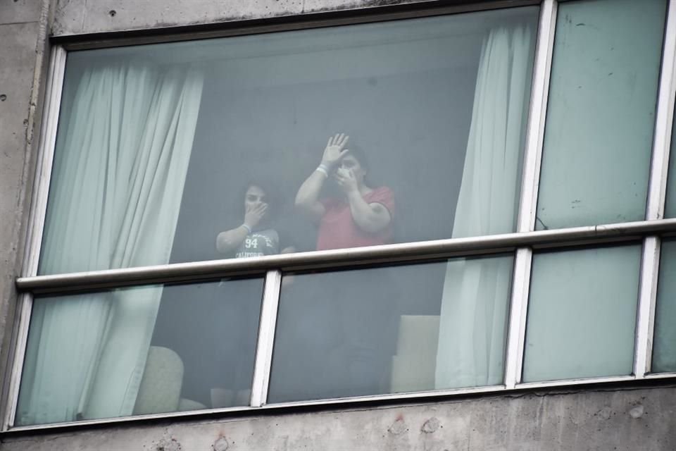 Migrantes deportados por Estados Unidos saludan a la prensa desde el interior de un hotel, el 19 de febrero de 2025, en Ciudad de Panamá.