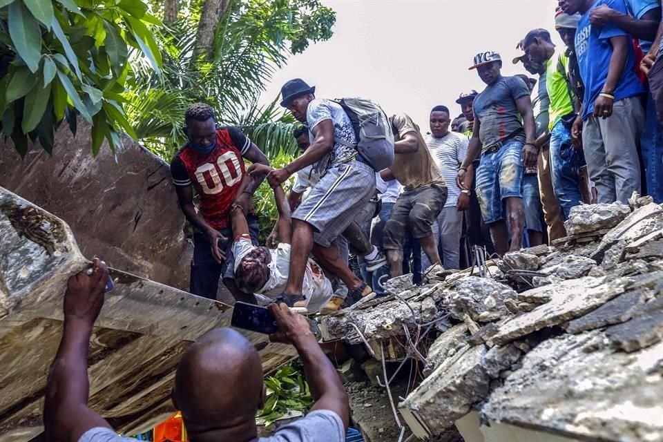 Personas ayudaban a sacar a los sobrevivientes y cuerpos de fallecidos de los escombros.