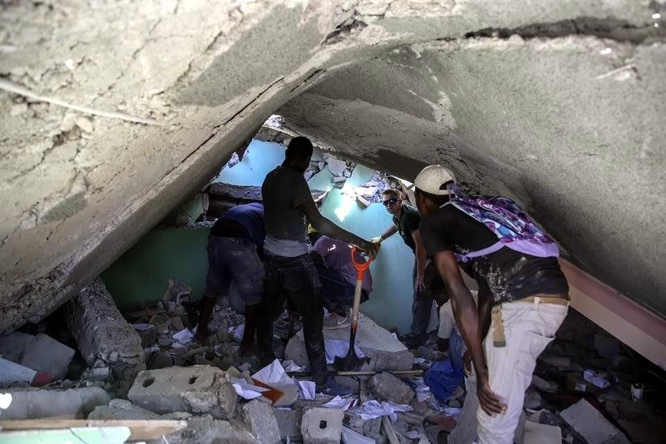 Personas buscan por sobrevivientes entre los escombros de un edificio en Les Cayes.