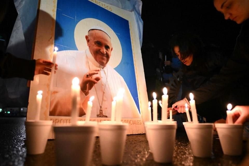 Fieles católicos encienden velas junto a una imagen del apa Francisco frente a la Catedral de Buenos Aires.