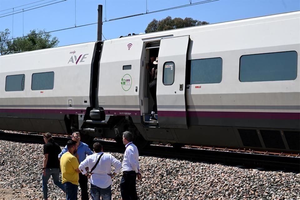 Pasajeros permanecen de pie y esperan junto a un tren AVE de alta velocidad de RENFE detenido cerca de Córdoba debido al corte del suministro eléctrico.