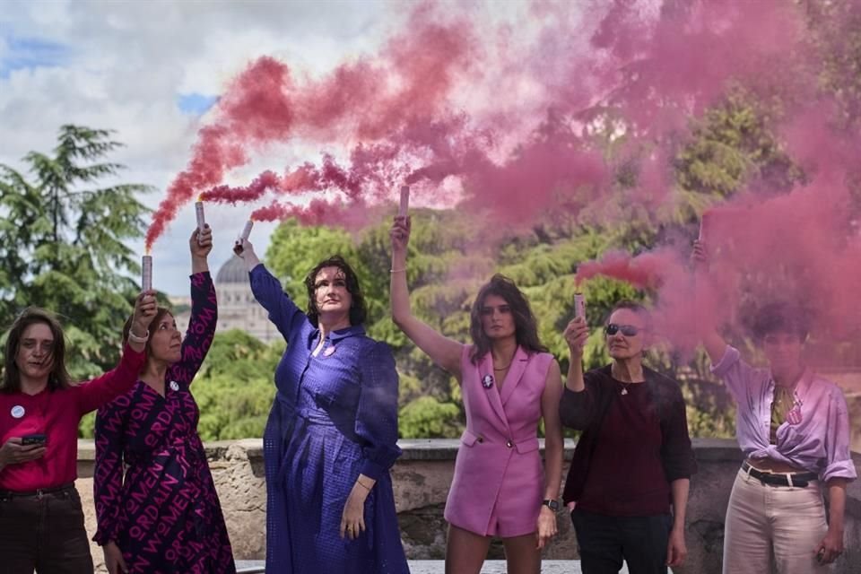 Activistas ondean bengalas de humo rosa durante el inicio del Cónclave el 7 de mayo del 2025.