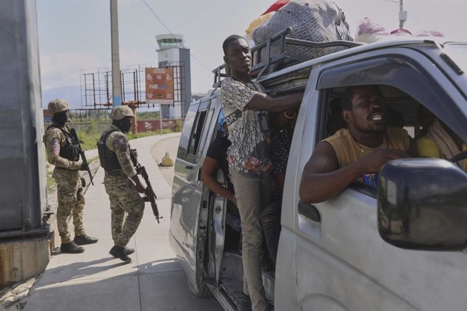 Un grupo de personas pasa frente a varios policías que patrullan una intersección, en Puerto Príncipe, Haití, el 9 de mayo de 2025.