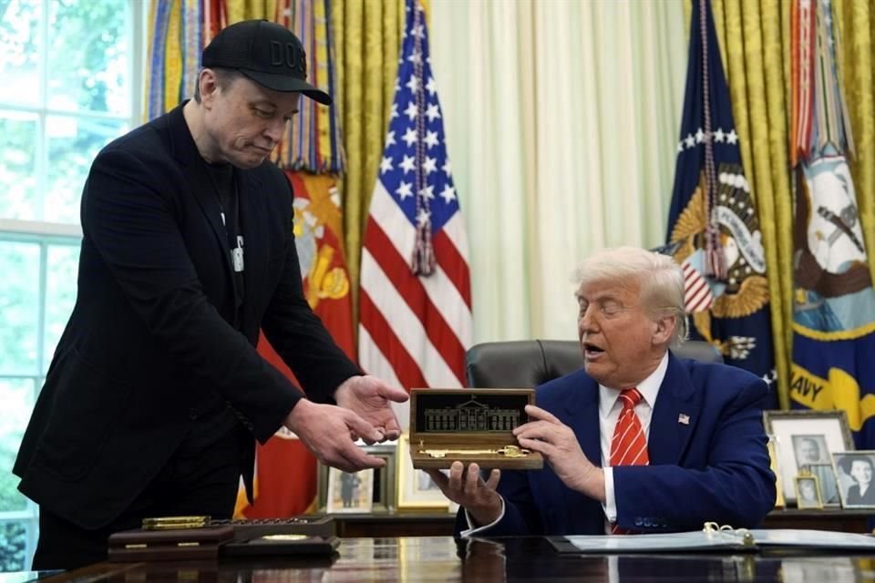 El presidente Donald Trump (derecha) le entrega una llave a Elon Musk durante una conferencia de prensa en la Oficina Oval de la Casa Blanca.