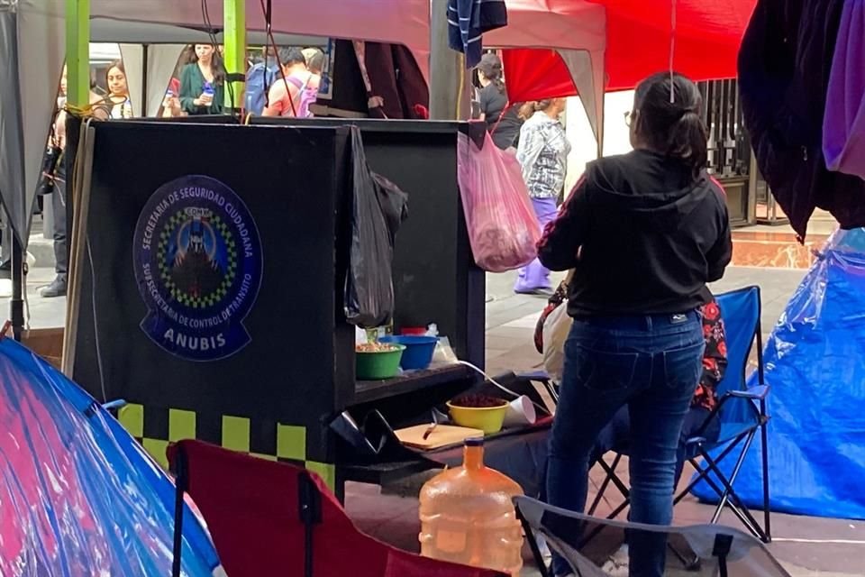 Una mujer usa mobiliario de la Secretaría de Seguridad Ciudadana como mesa para preparar alimentos.