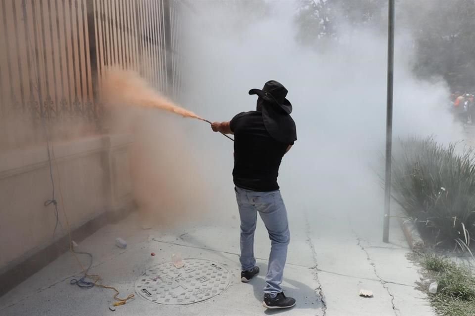 Otro sujeto arrojó el mismo material de vuelta a los agentes que vigilan el inmueble, según imágenes captadas por Grupo REFORMA.