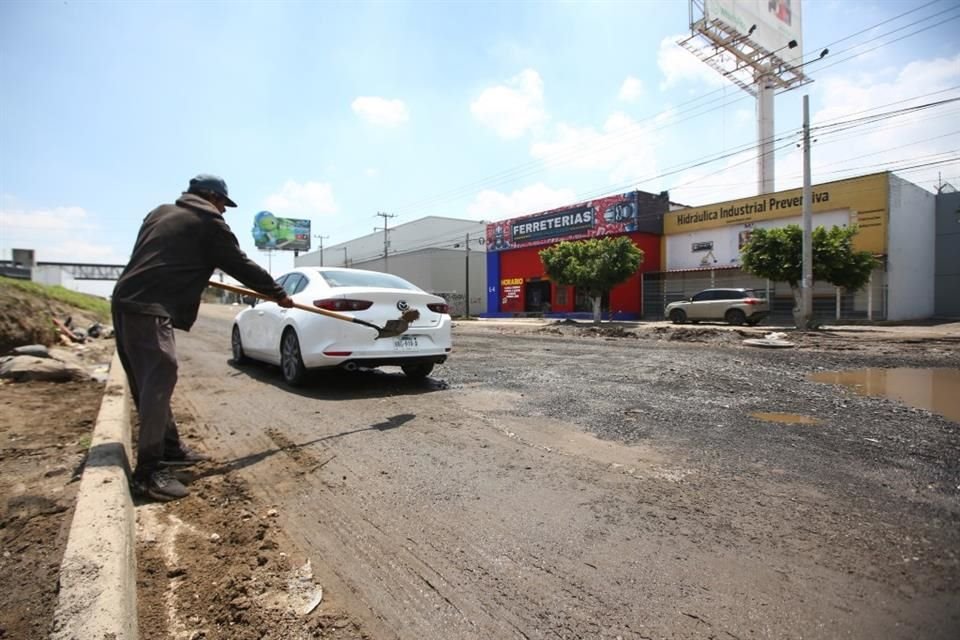 En la lateral del Periférico y la Calle del Panadero, personas tapan los baches a cambio de alguna moneda.
