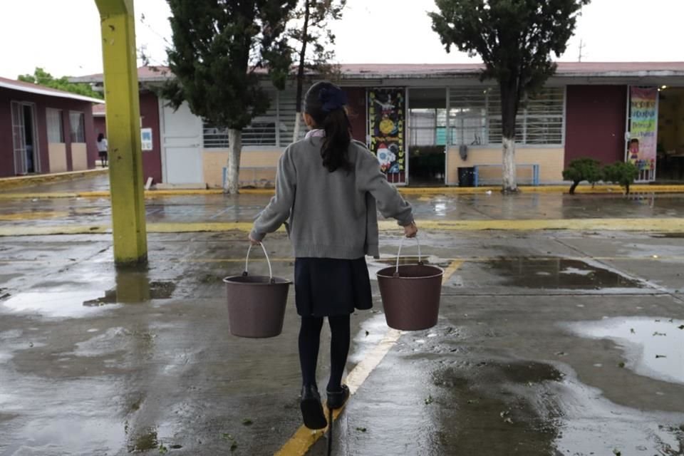 Menores acarrean agua en cubetas para llevarla a distintos puntos del plantel, ya sean baños o salones.