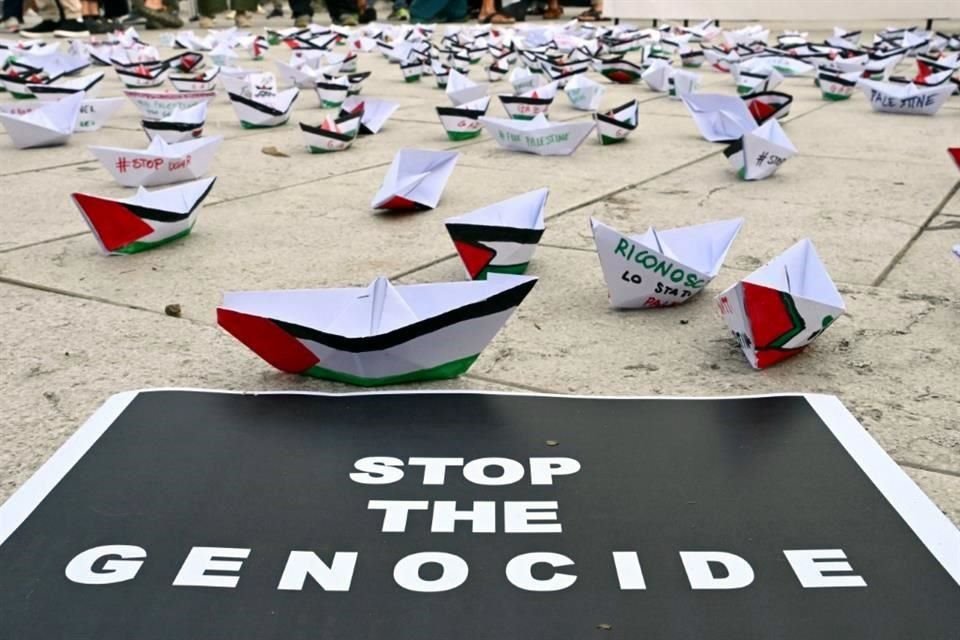 Una flotilla de barcos de papel está colocada en el suelo cerca de un cartel que dice 'Alto al genocidio' durante una manifestación en apoyo de Gaza y del pueblo palestino en el Lido de Venecia.