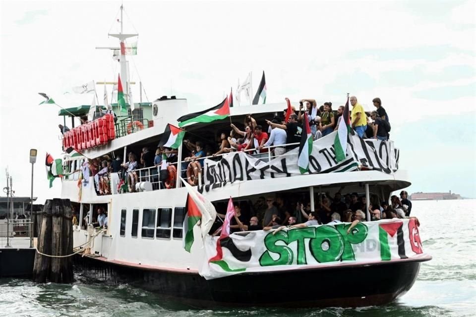 Personas a bordo de un barco ondean banderas palestinas cuando llegan para participar en una manifestación en apoyo de Gaza y el pueblo palestino en el 82 Festival Internacional de Cine de Venecia.