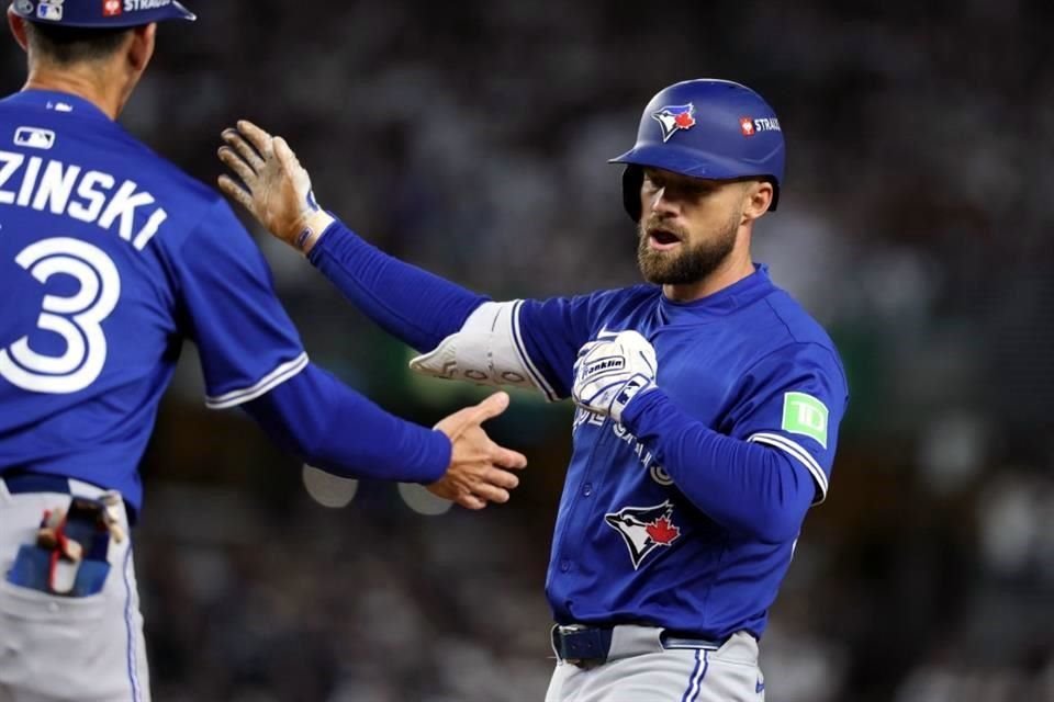 Nathan Lukes, de los Toronto Blue Jays, celebra con Mark Budzinski tras conectar un sencillo impulsor de dos carreras contra los Yankees.