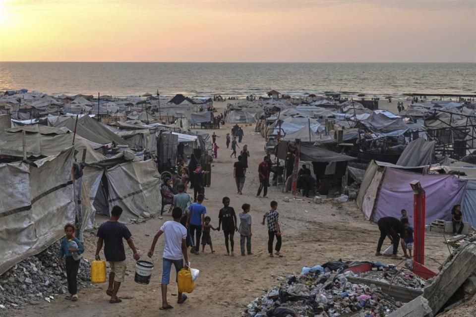 Palestinos desplazados caminan por un campamento improvisado en la playa de Ciudad de Gaza.