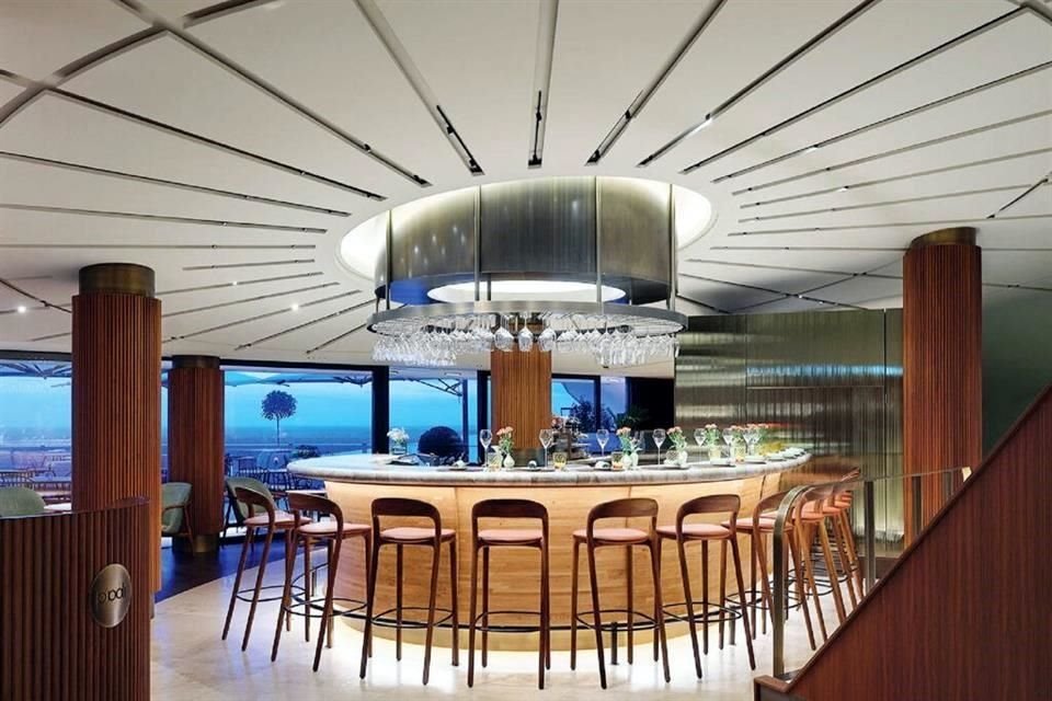 La barra de mármol del bar está iluminada por una lámpara de techo tubular que incluye un portacopas de acero inoxidable.