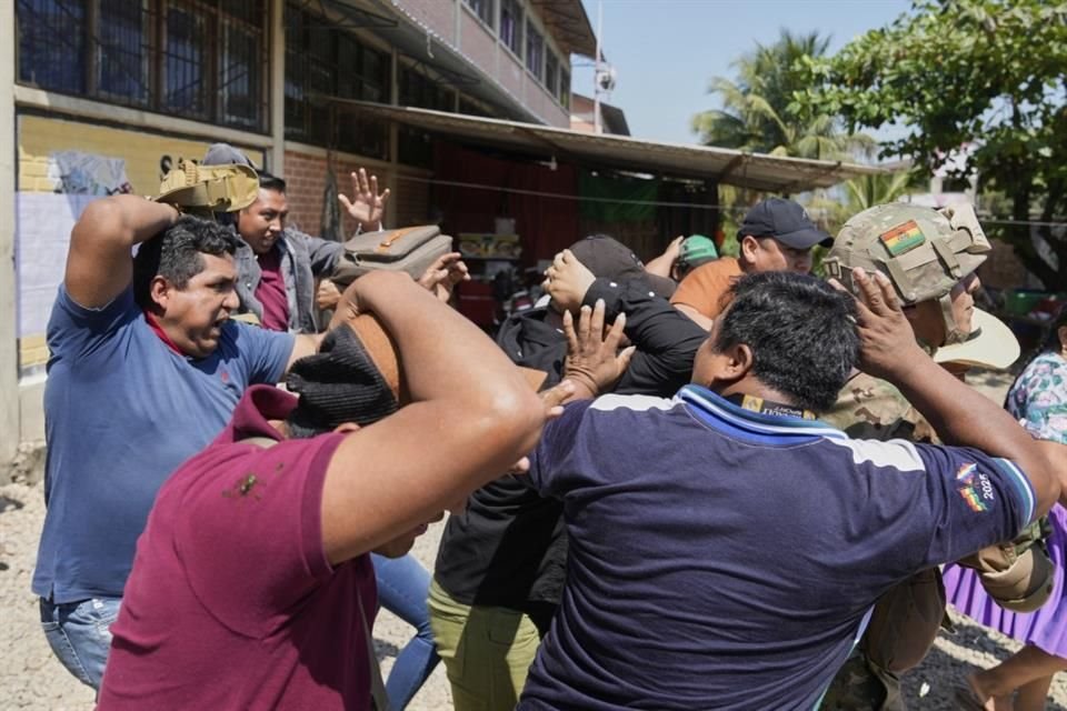 Personal de seguridad rodea al candidato presidencial izquierdista Andrónico Rodríguez mientras abandona un centro de votación después de votar y opositores le tiran piedras.