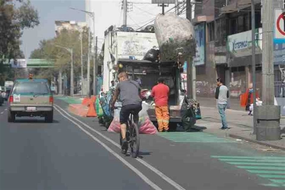 Camiones de basura ocupan todo el carril confinado mientras recolectan los residuos de los domicilios aledaños.
