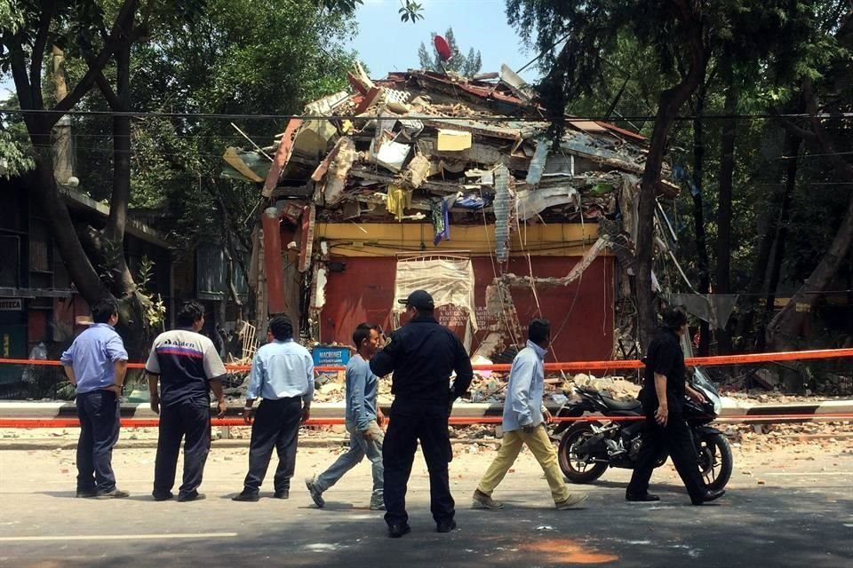 Personas caminan frente a un edificio derrumbado despus del sismo.