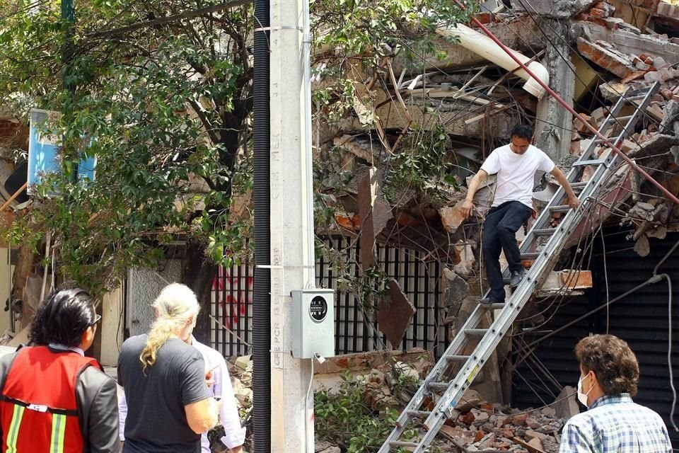 Vecinos inspeccionan un edificio derrumbado.