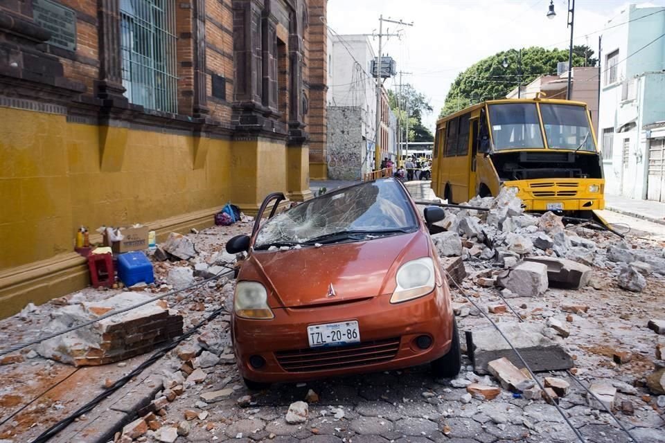Un automvil qued destrozado por los trozos de concreto que se desprendieron de un edificio, en el Centro de Puebla.