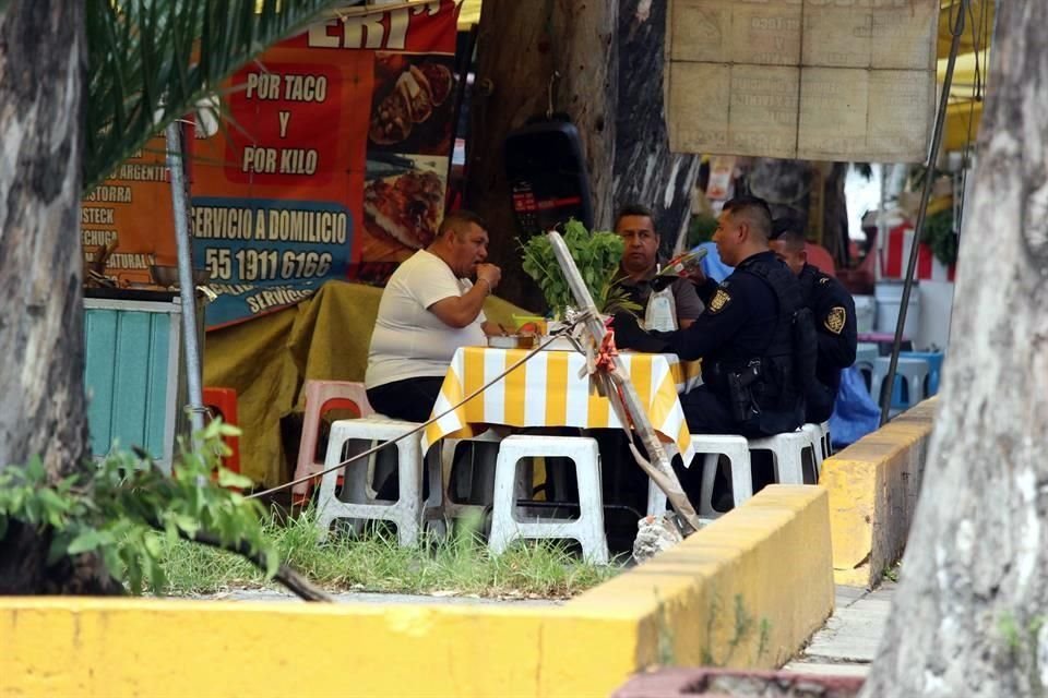 Policas del Sector Santa Fe aprovechan un descanso para comer en un puesto de tacos de carnitas.