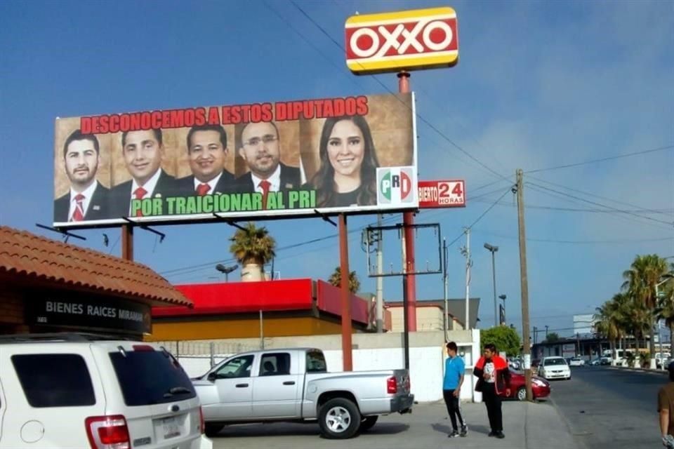 En el letrero sobresalen los rostros de los cinco priistas que votaron a favor del cambio en la Constitución.