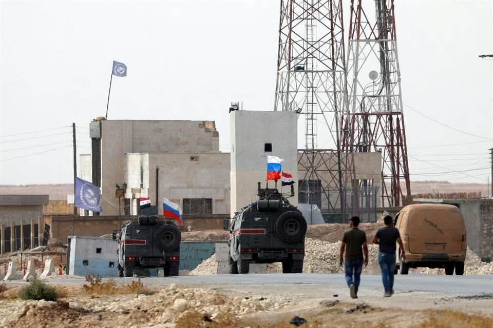 Vehículos con las banderas de Siria y Rusia pasan por Manbij.