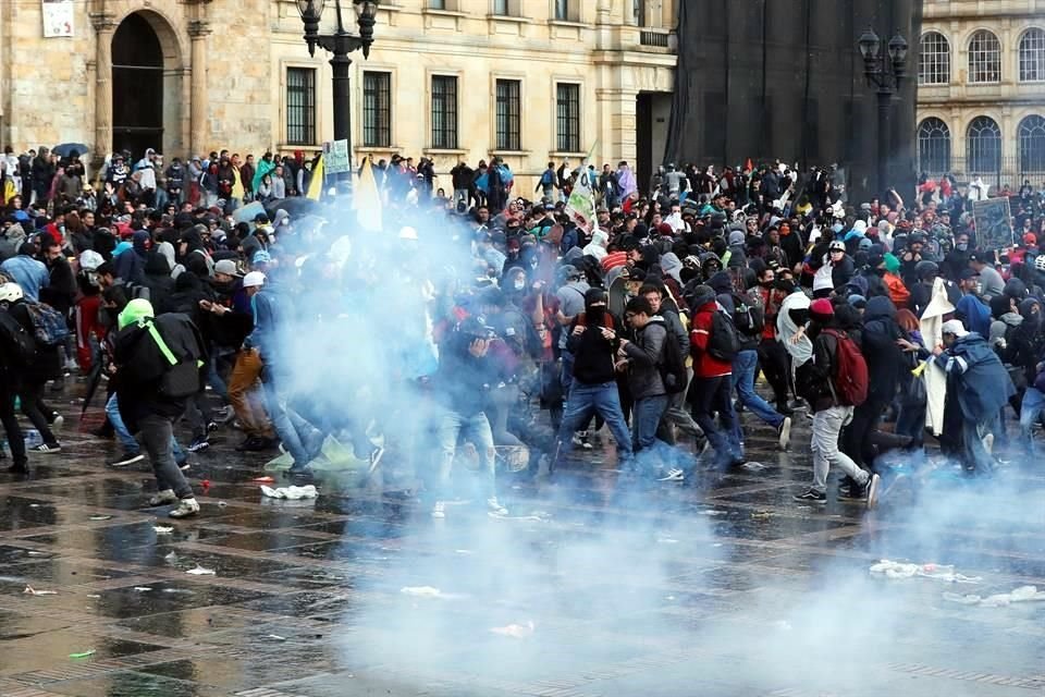 Decenas de personas corren de los gases lacrimógenos lanzados por miembros de la Policía antidisturbios en la Plaza de Bolívar.