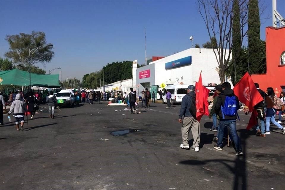 Con banderas rojas en mano, los integrantes de Antorcha Campesina se dirigen a los camiones para abordarlos rumbo a sus entidades de origen.
