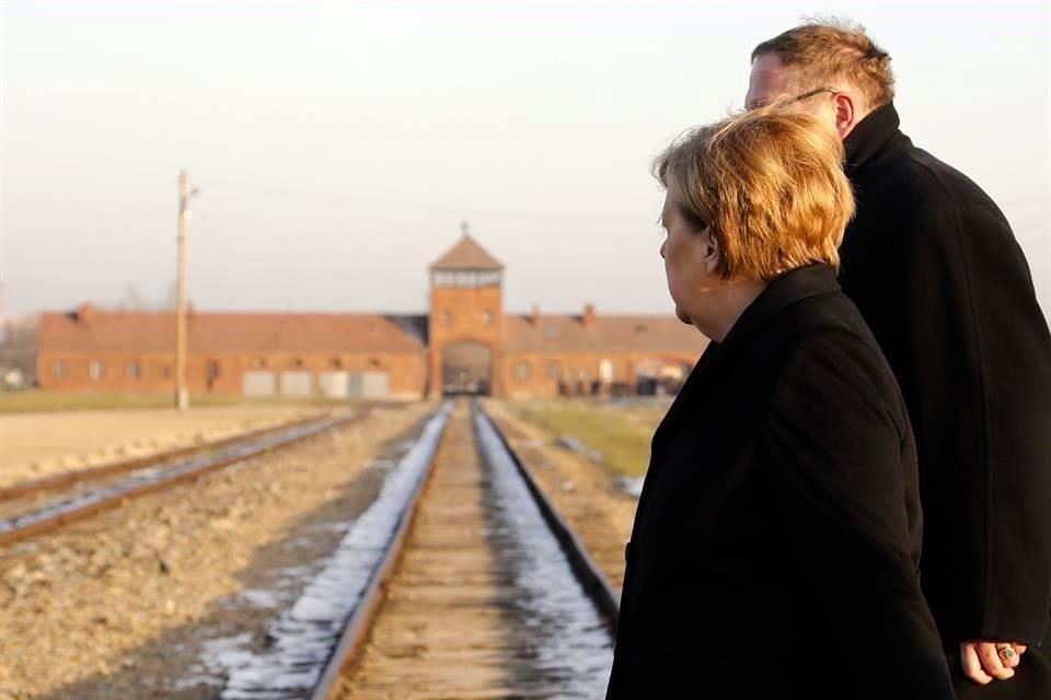 Merkel junto al director del museo, en las vías del tren que llevaba al campo de concentración.