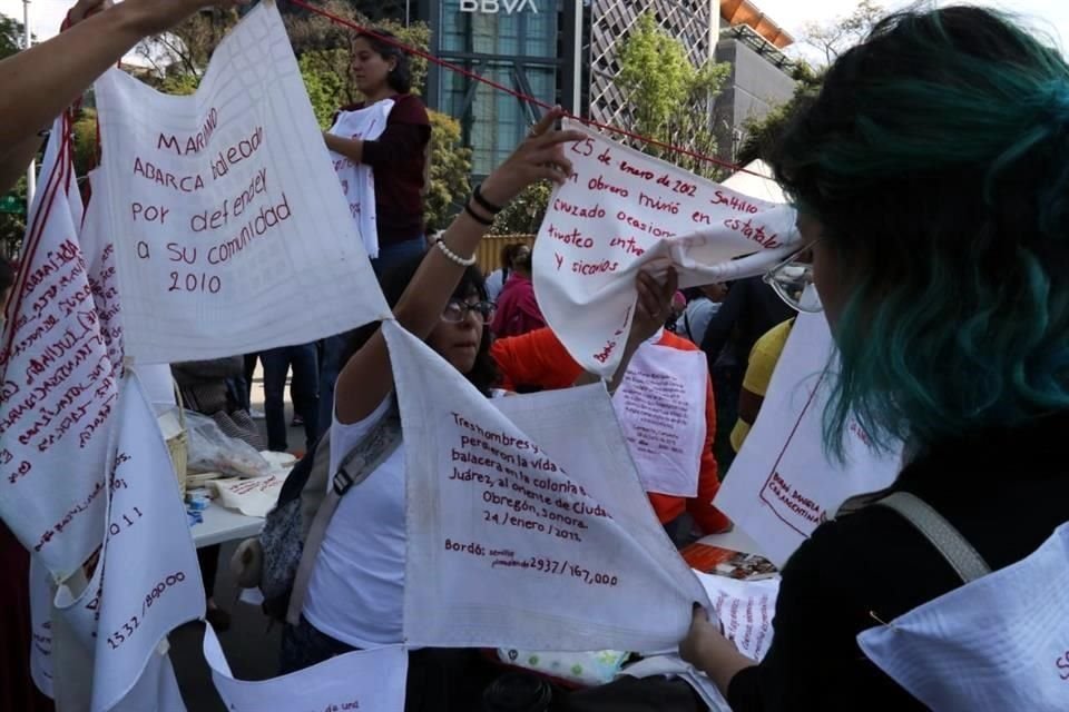Frente a la Estela de la Luz, organizaciones de víctimas han colgado pañuelos bordados con el nombre de sus familiares.