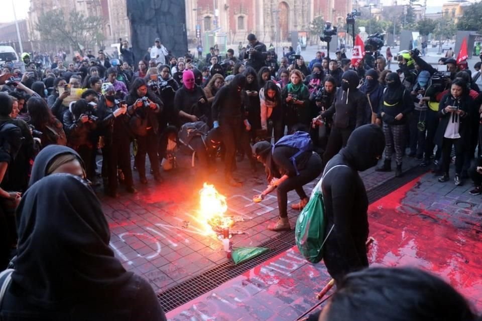 Mujeres encapuchadas realizan quemas y pintas afuera de Palacio Nacional.