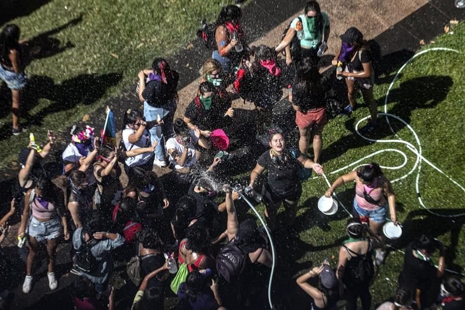 Mujeres se lavan con agua luego de que la Policía de Chile les arrojara gas lacrimógeno.