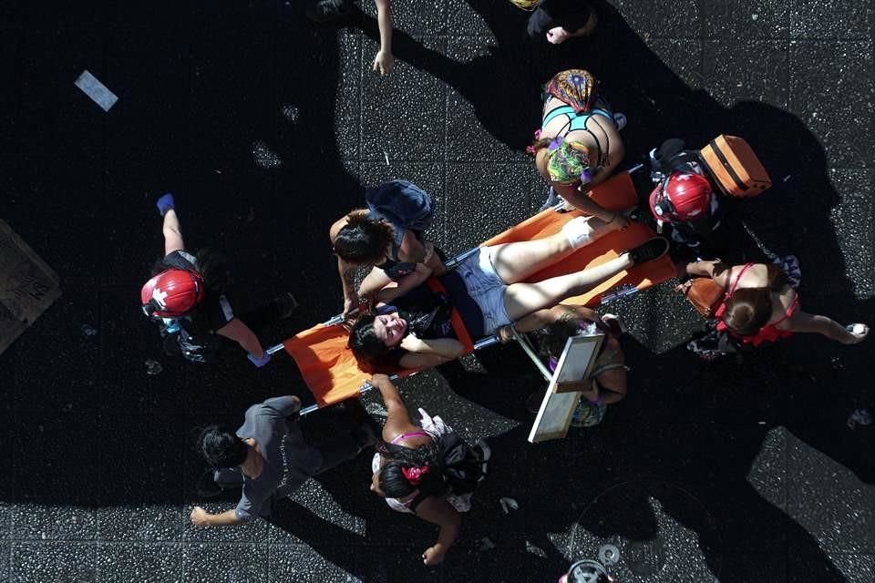 Una mujer lastimada es llevada por un grupo de voluntarios médicos durante la marcha en Chile.