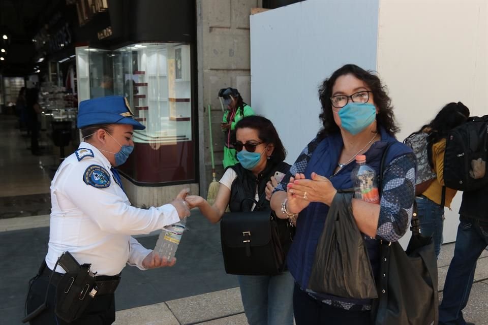 En calles de la CDMX, policías reparten gel antibacterial a los peatones.