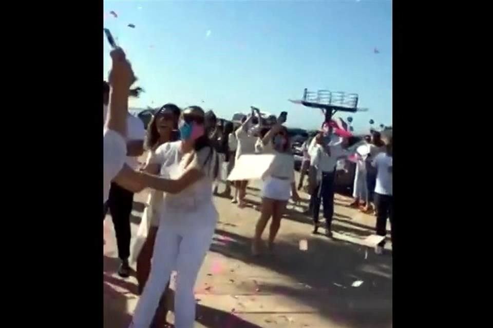 En un video se observa a personas vestidas de blanco y a algunas de ellas portando cubrebocas.