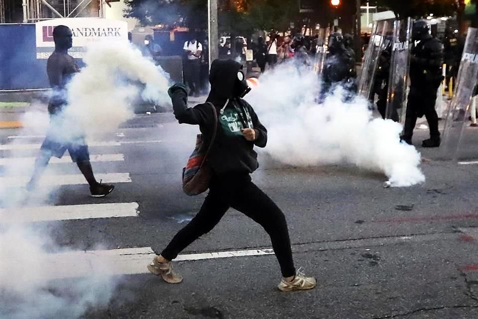 Un manifestante regresa una lata con gas lacrimógeno a policías en Atlanta.