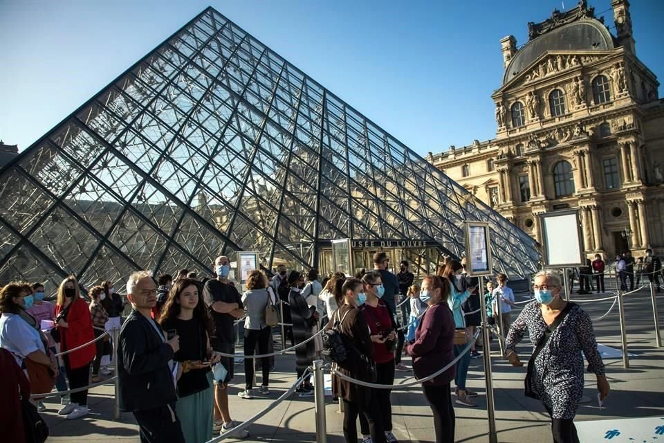 Visitantes con mascarillas protectoras esperan formados a entrar al Museo del Louvre.