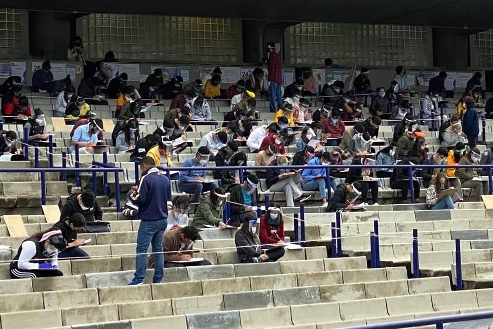 Los aspirantes están sentados en las gradas del Estado Olímpico de CU, y se les dio una tablilla para contestar el examen, todos llevan cubrebocas y caretas.