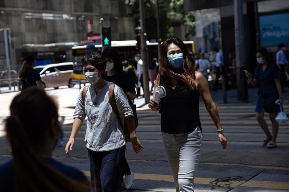 Las personas en el distrito central de Hong Kong usan cubrebocas mientras caminan por la calle.