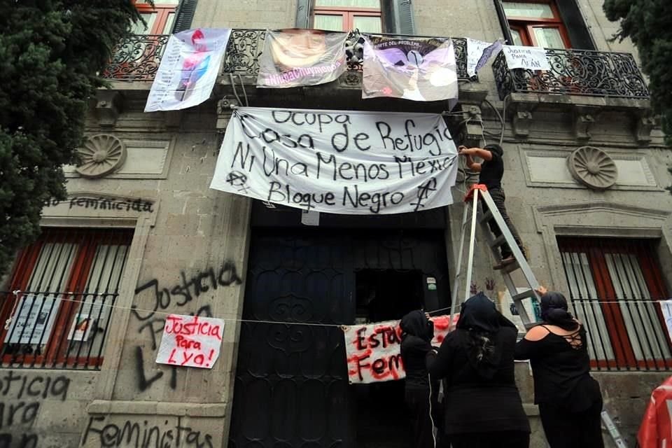 Las mujeres colgaron una manta blanca con letras negras que dicen 'Ocupa Casa de Refugio Ni Una Menos México. Bloque Negro'.