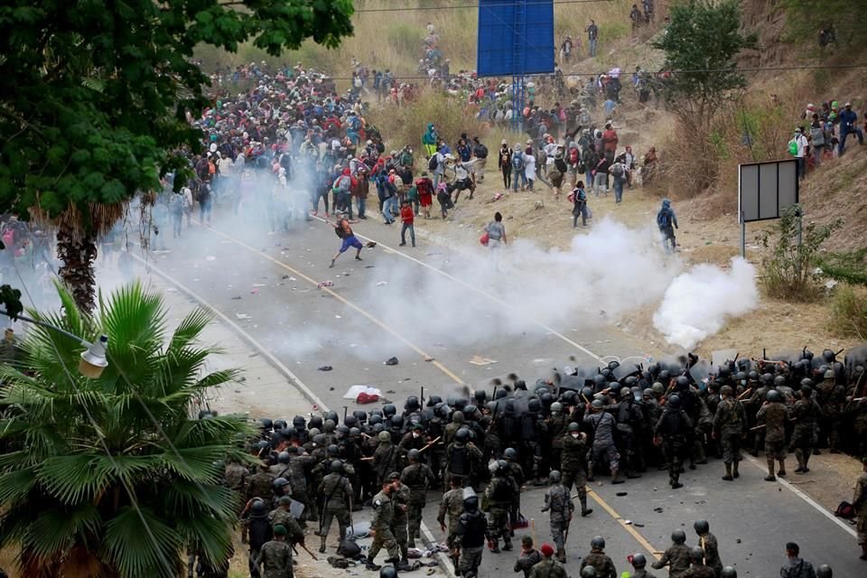 Soldados y policías guatemaltecos forman una barricada humana y lanzan gases lacrimógenos para detener a los migrantes hondureños que caminan por una carretera.